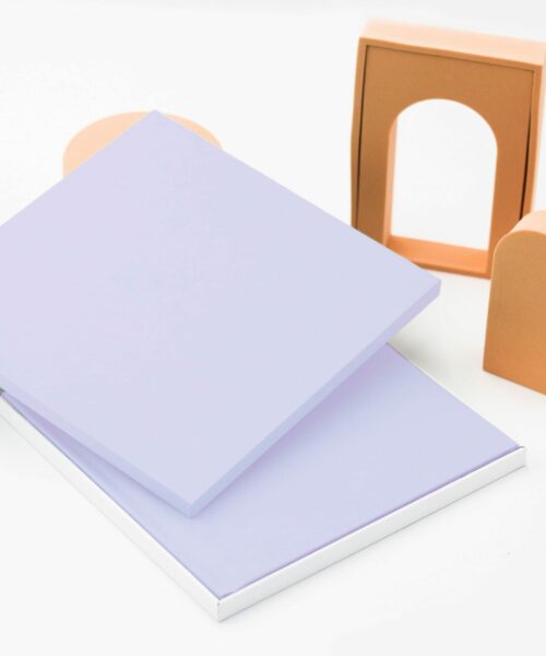 An open lilac-coloured square presentation box with a photobook of the same colour inside